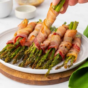 Bacon wrapped asparagus on a white plate.