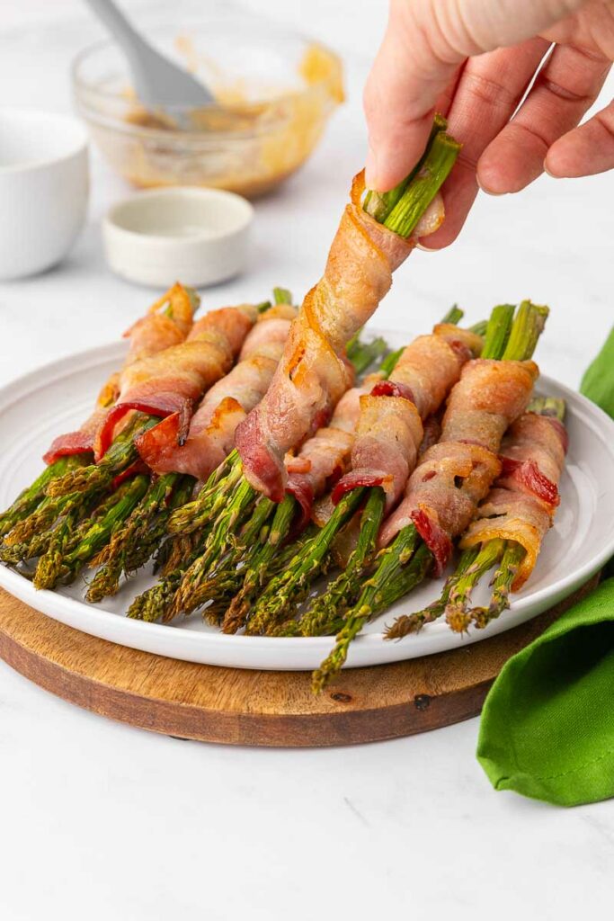 Bacon wrapped asparagus on a white plate.