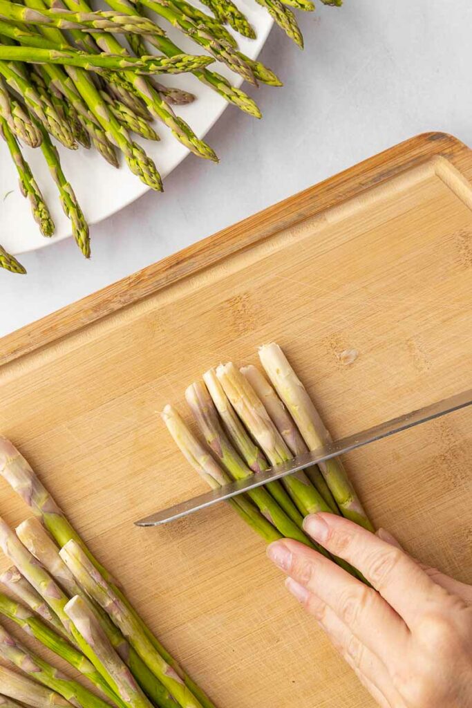 Trimming the ends off asparagus with a knife.