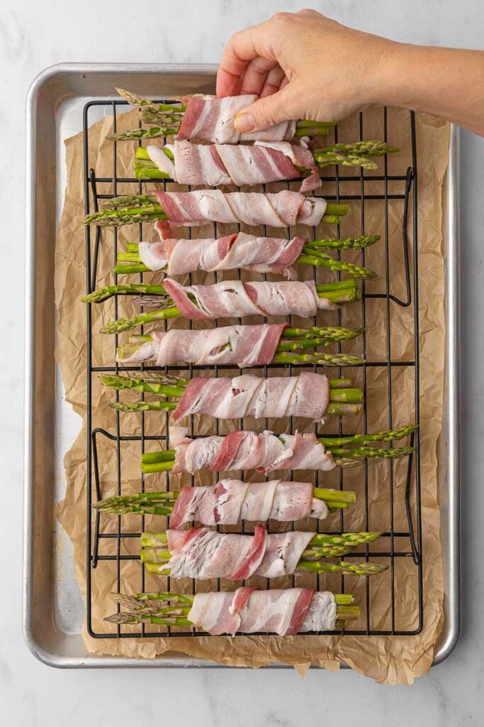 Bacon wrapped asparagus on a wire rack ready to cook.