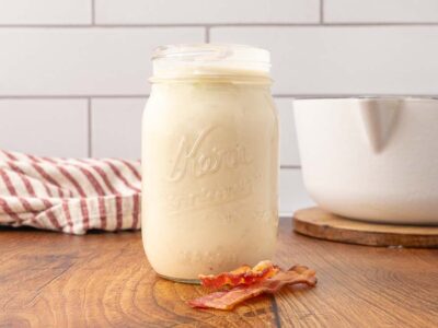 A Mason jar of cream of bacon soup on a wooden counter.