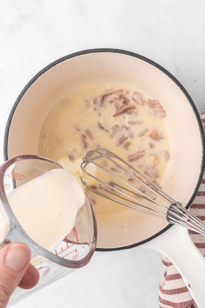 Cream being poured into a cream of bacon soup.