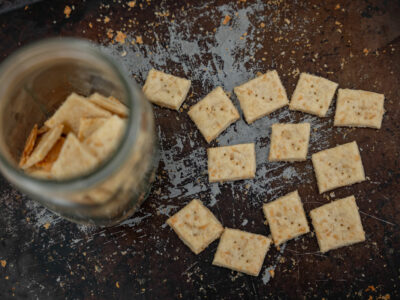 Homemade crackers on a cooking sheet and some crackers in a Mason jar.