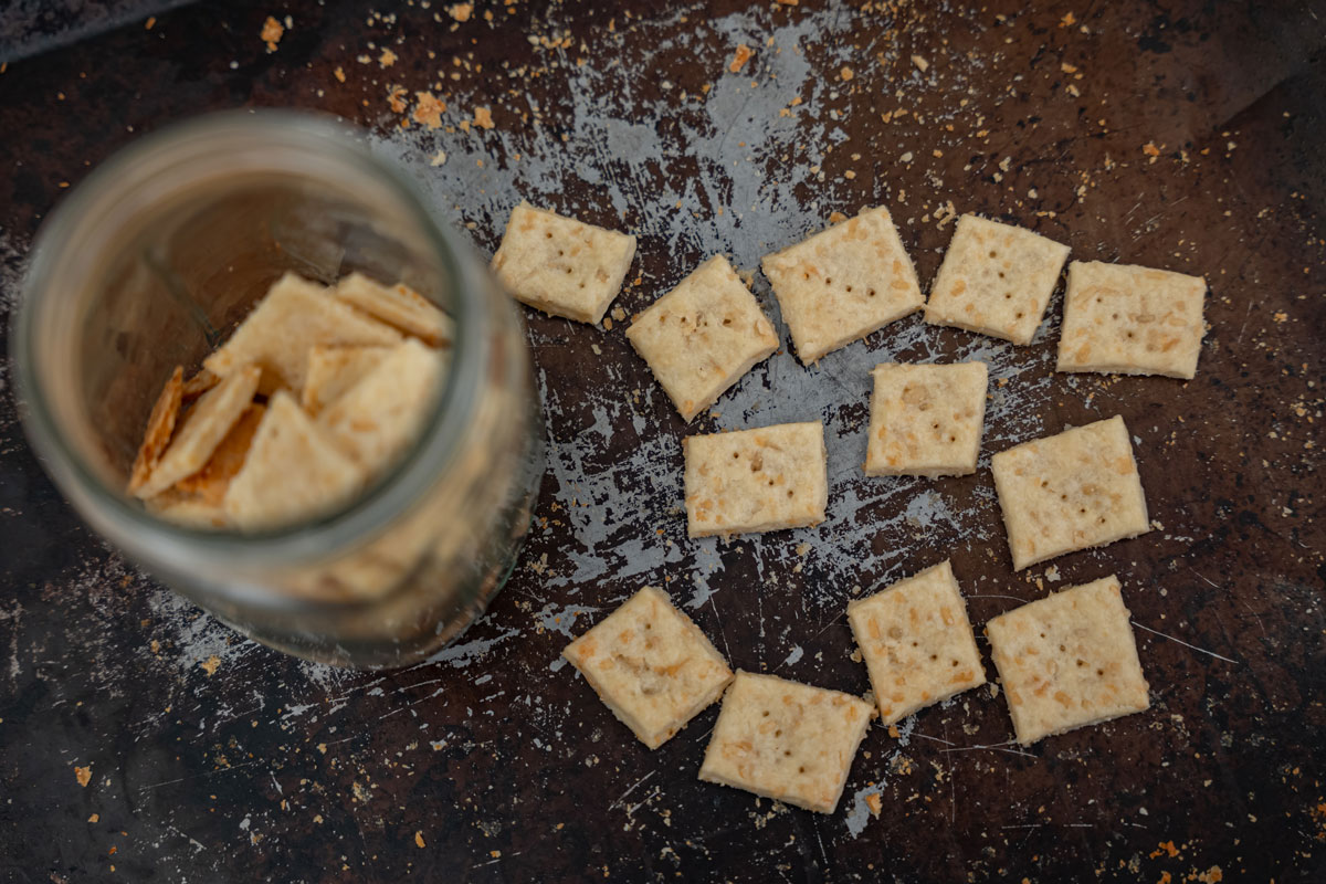 Homemade crackers on a cooking sheet and some crackers in a Mason jar.