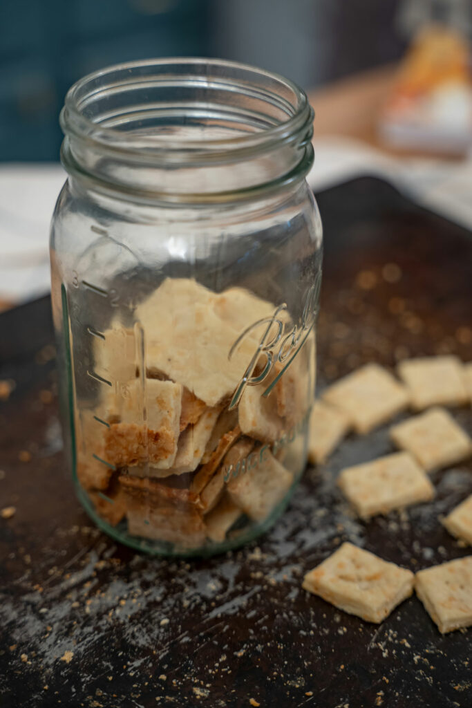 Homemade crackers on a cooking sheet and some crackers in a Mason jar.