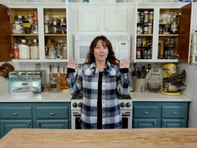 A woman pointing to items in her kitchen cupboard.