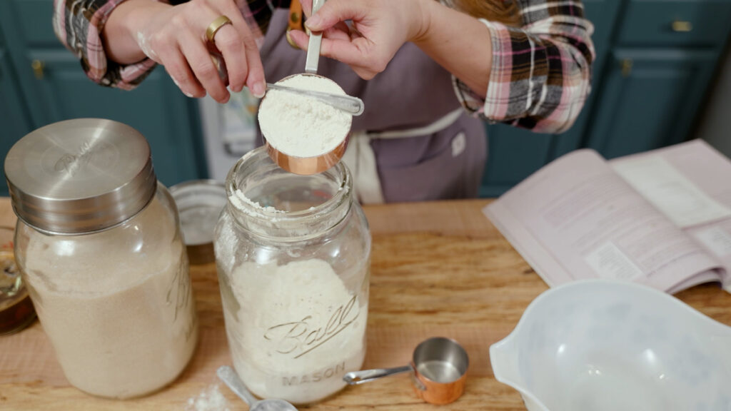 A woman measuring a cup of flour.