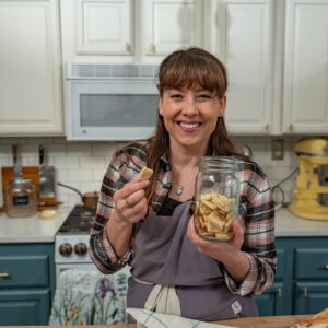 A woman holding a jar of homemade crackers.