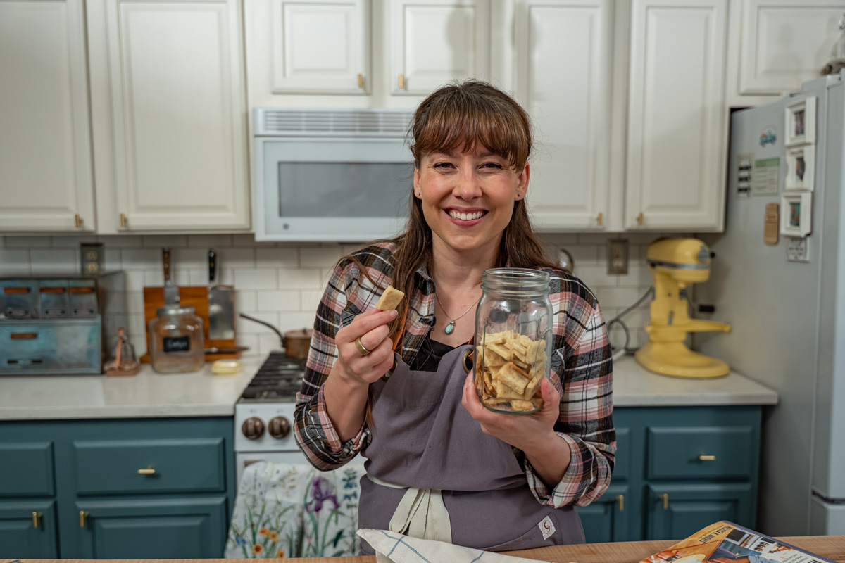 A woman holding a jar of homemade crackers.