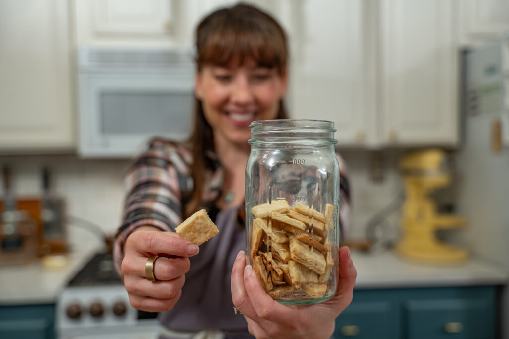 A woman holding a jar of homemade crackers.