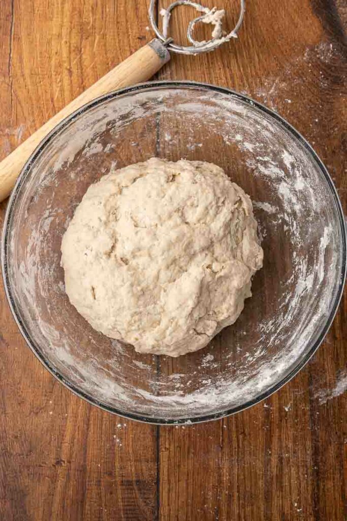 A ball of no-knead bread dough sitting in a glass bowl.