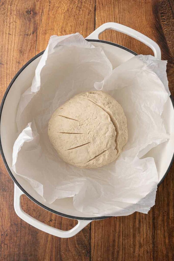 No knead bread dough in a parchment lined Dutch oven.