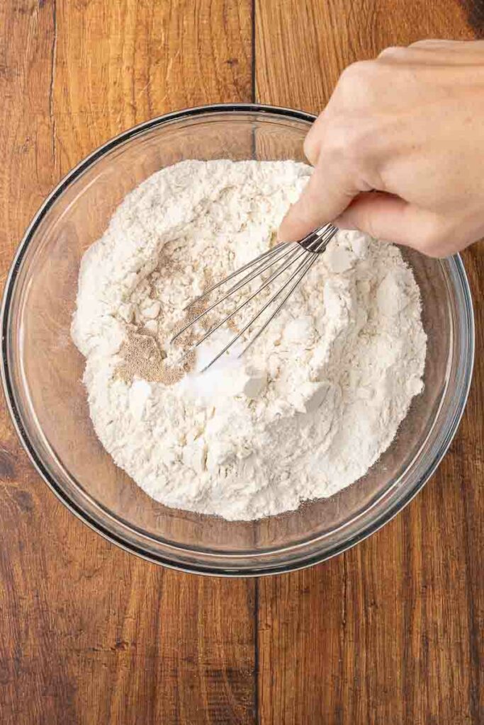 Whisking together flour, salt and yeast in a glass bowl.