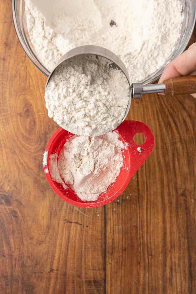 Dry ingredients for no-knead bread dough being funneled into a Mason jar.