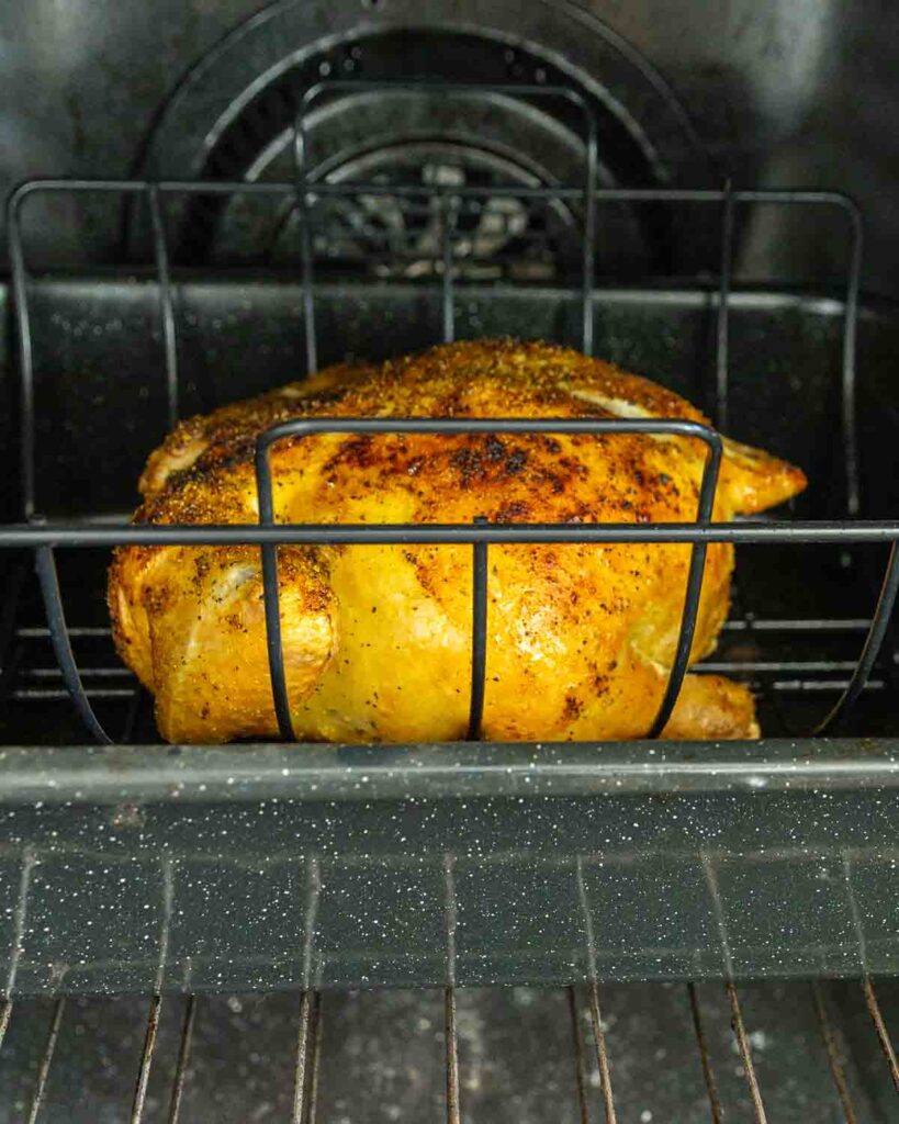 A whole chicken roasting in an oven.