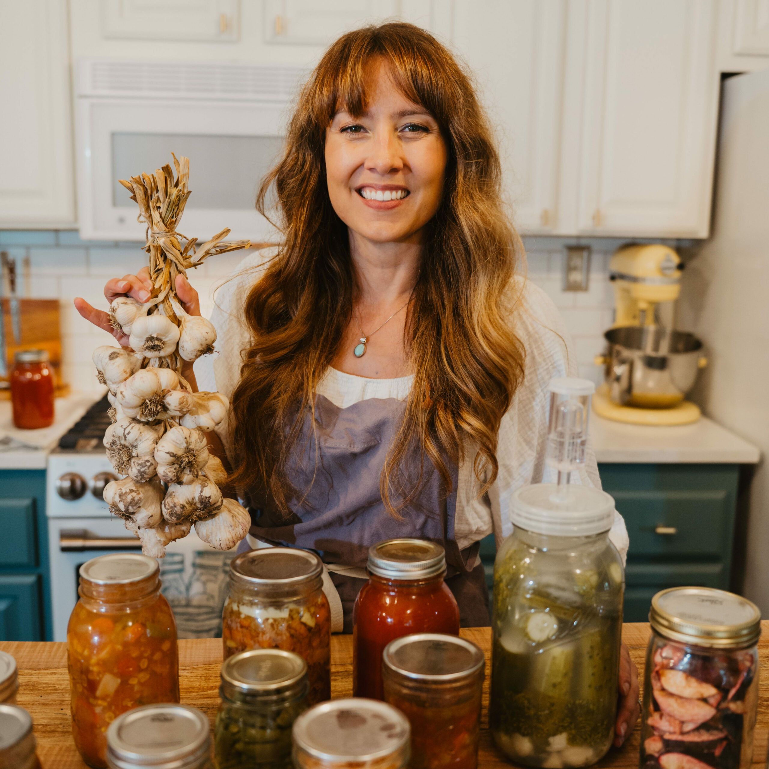 A woman in the kitchen with jars of home canned food.