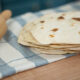 A stack of sourdough tortillas on a towel lined counter.