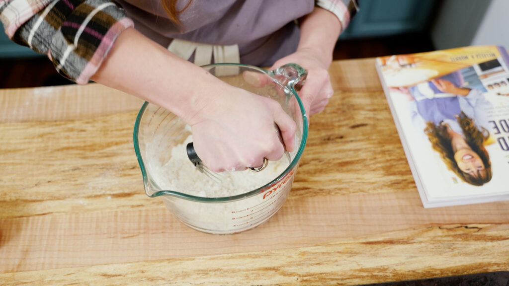 Butter being cut into flour with a pastry knife.