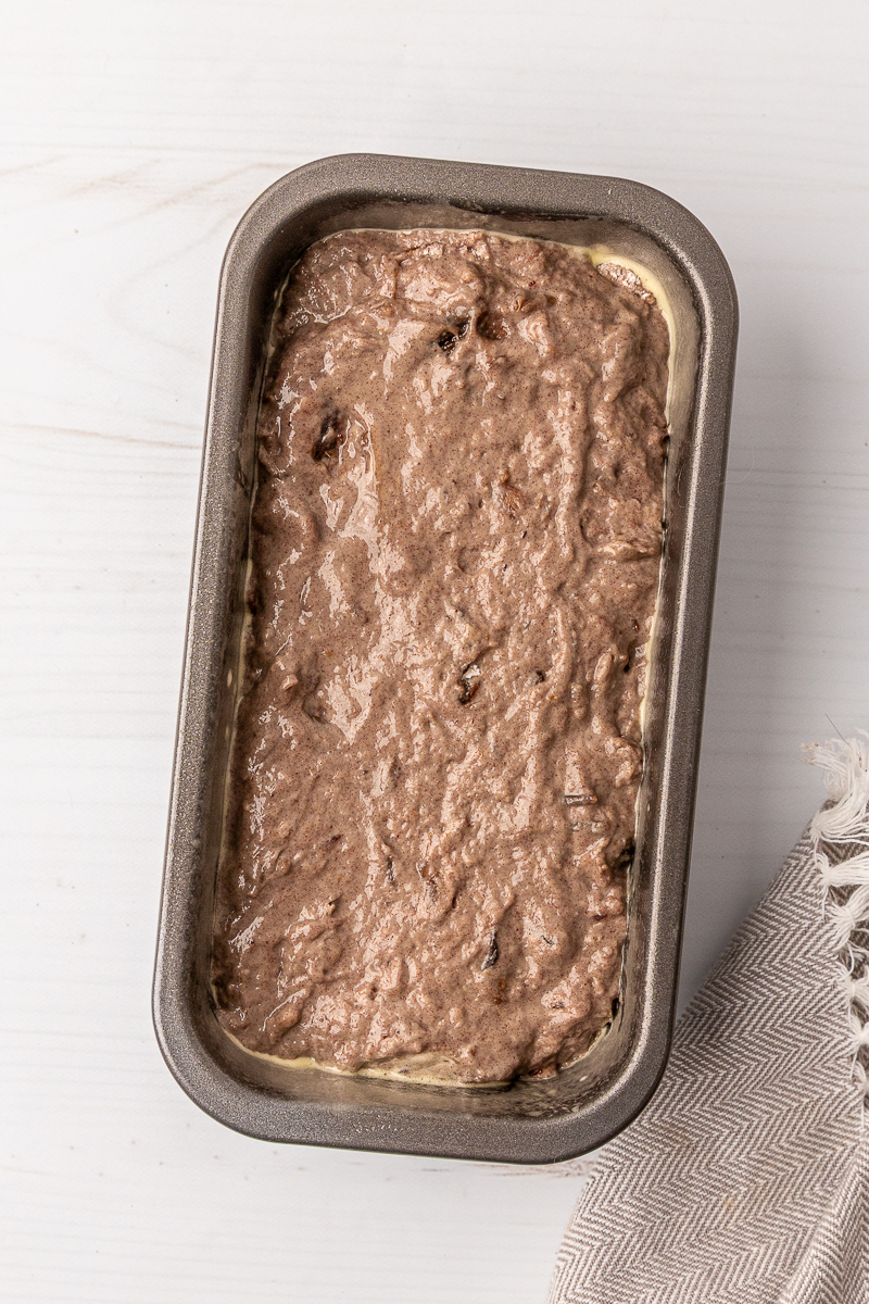 A loaf pan with date bread batter inside.