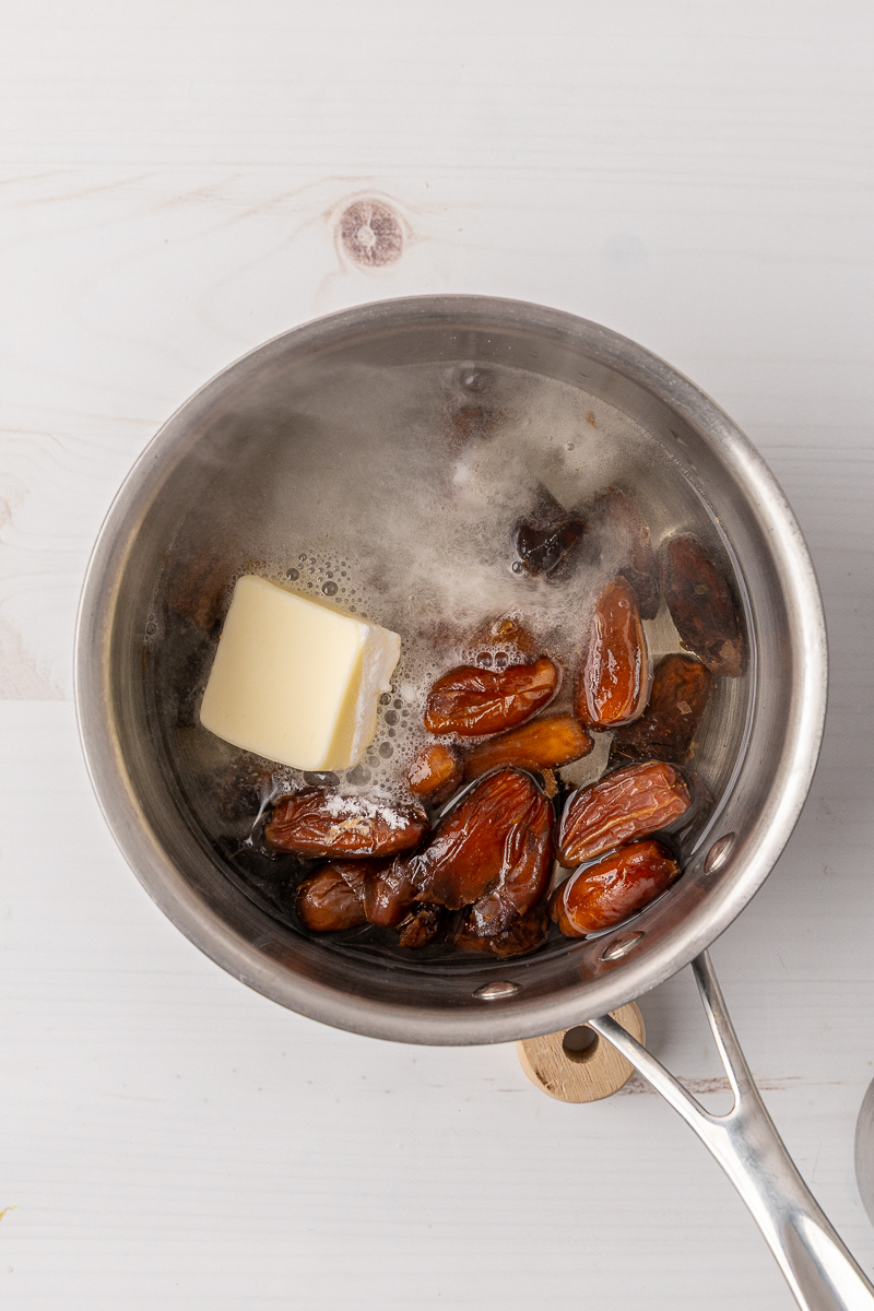 Dates and butter being boiled in a small sauce pan with water.