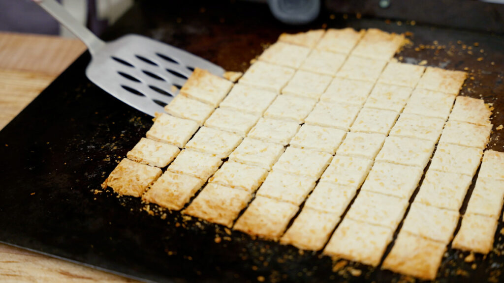 Homemade crackers being removed from the pan with a spatula.