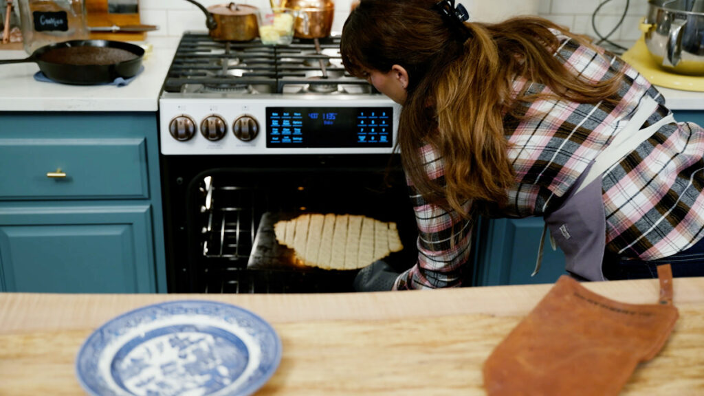 A woman pulling homemade crackers out of the oven.