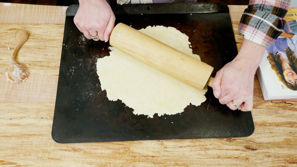 Cracker dough being rolled out on a baking sheet.