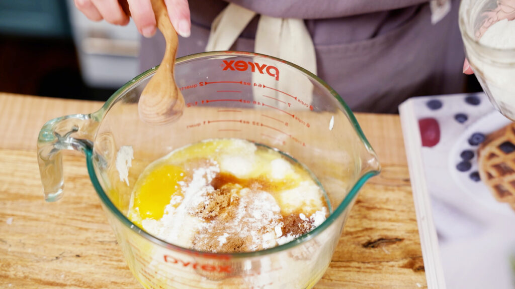 A mixing bowl with sourdough pancake batter being stirred together.