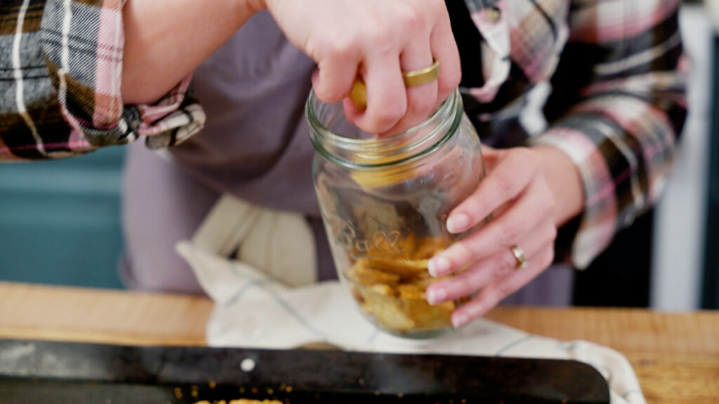 Homemade crackers being put into a Mason jar.