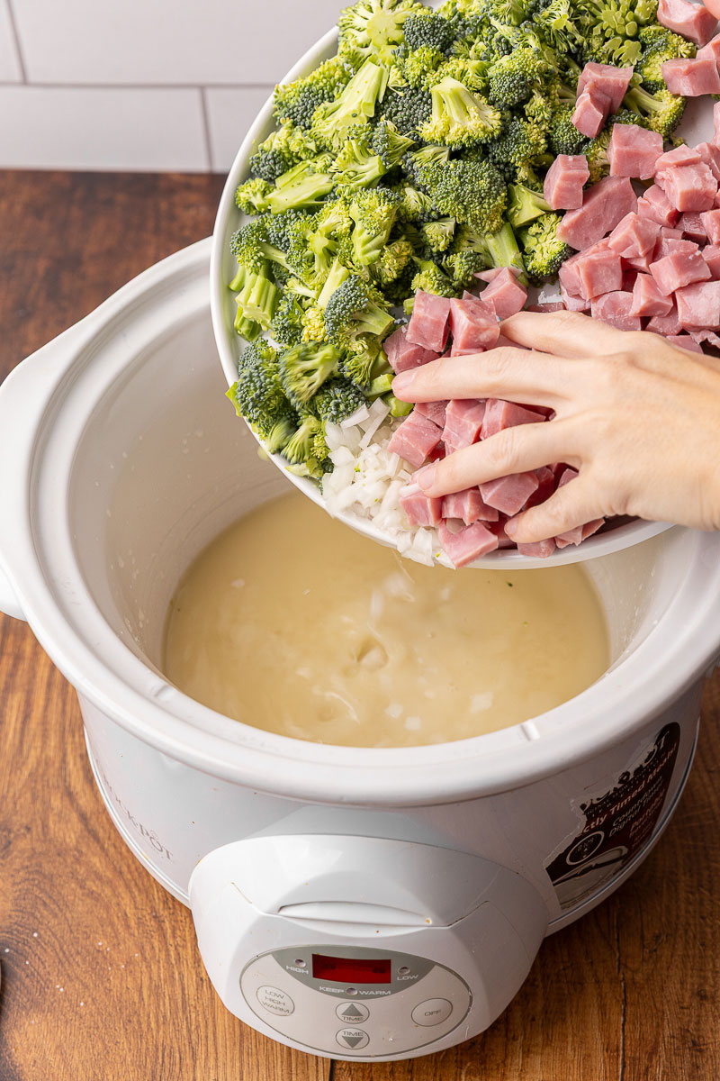 Broccoli and ham and onions being added to a crockpot.
