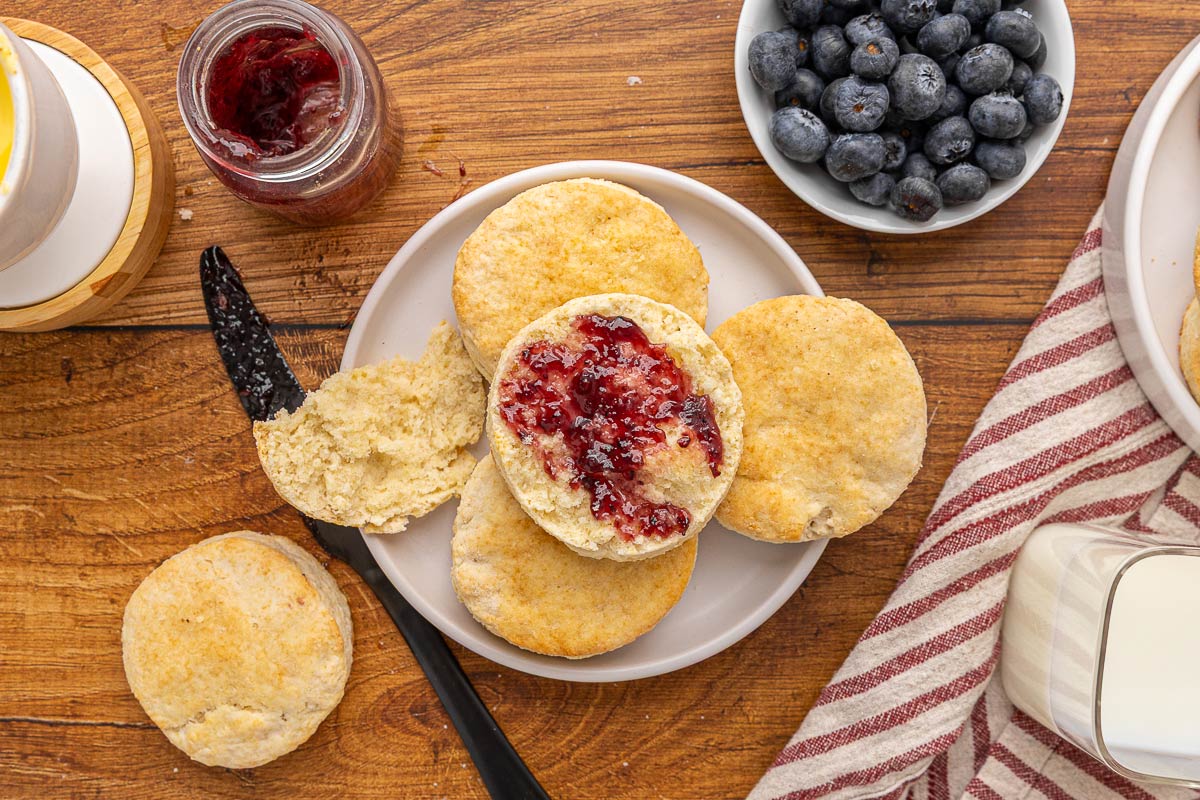 Biscuit cut in half with butter and jam on a plate.