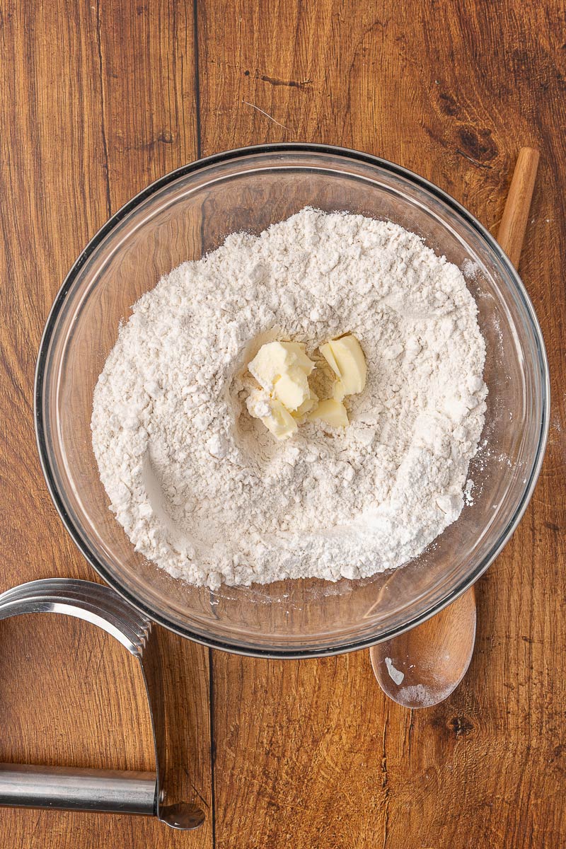 Dry ingredients with cubed butter in a mixing bowl for homemade biscuits.