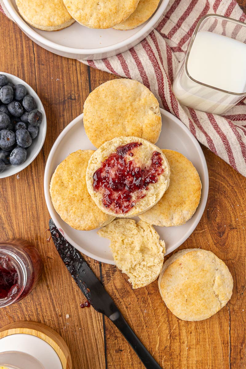 Biscuit cut in half with butter and jam on a plate.