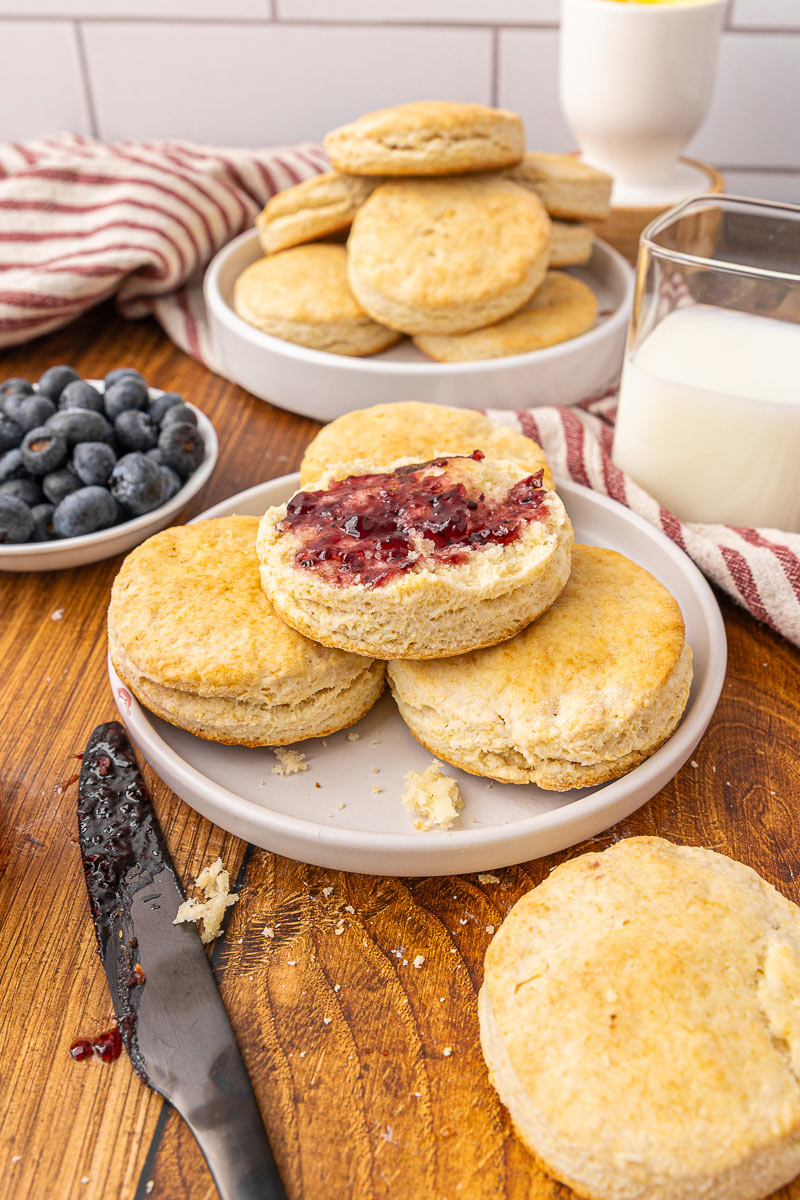 Biscuit cut in half with butter and jam on a plate.
