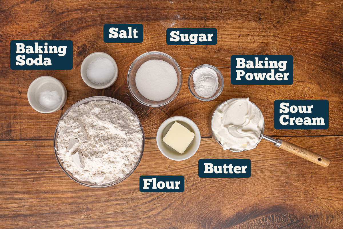Ingredients to make homemade sour cream biscuits on a wooden counter.
