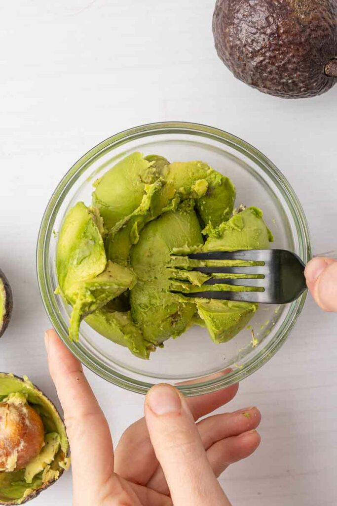 Mashing avocado with a fork.