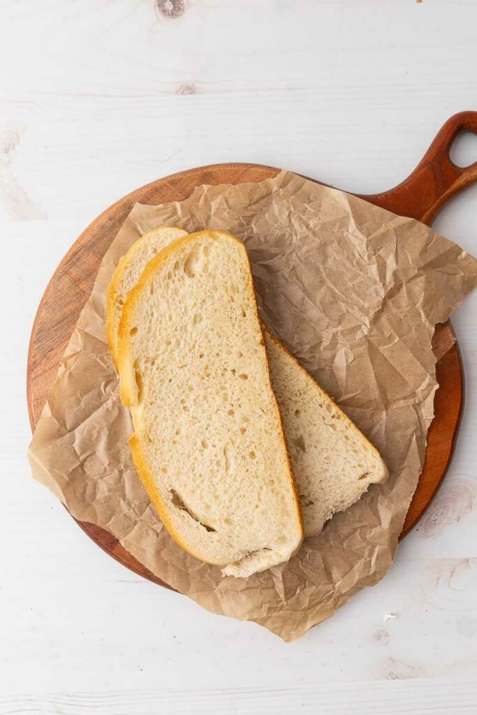 Two slices of bread on a piece of parchment paper.