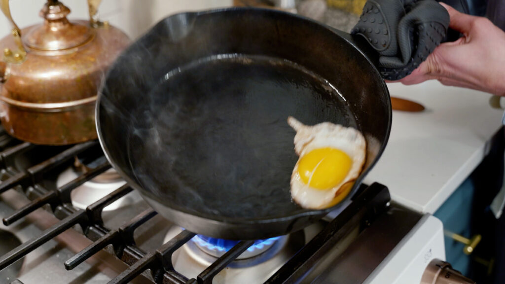 An egg cooking in a cast iron skillet.