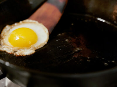 An egg cooking in a cast iron skillet.