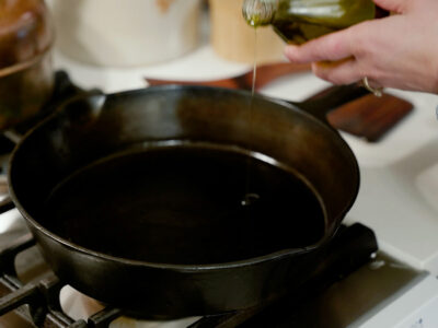 Oil being poured into a cast iron skillet.