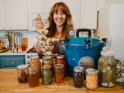 A woman with a counter full of preserved foods.