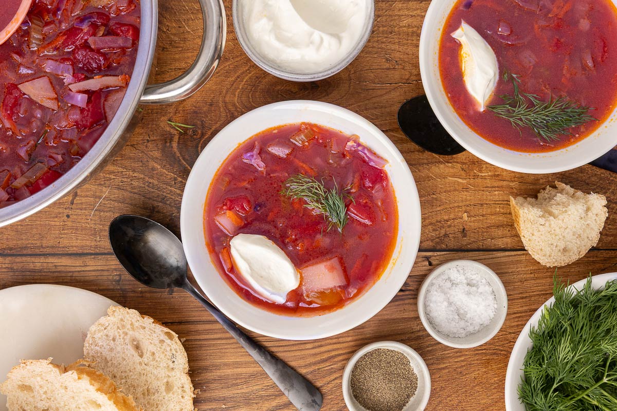 Bird's eye view of traditional Ukranian borscht served in bowls and garnished with sour cream.