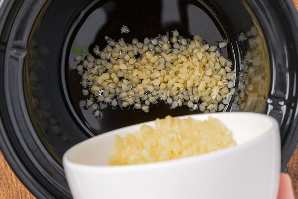 Combining beeswax and herbal infused oil into a crockpot to make an herbal salve.