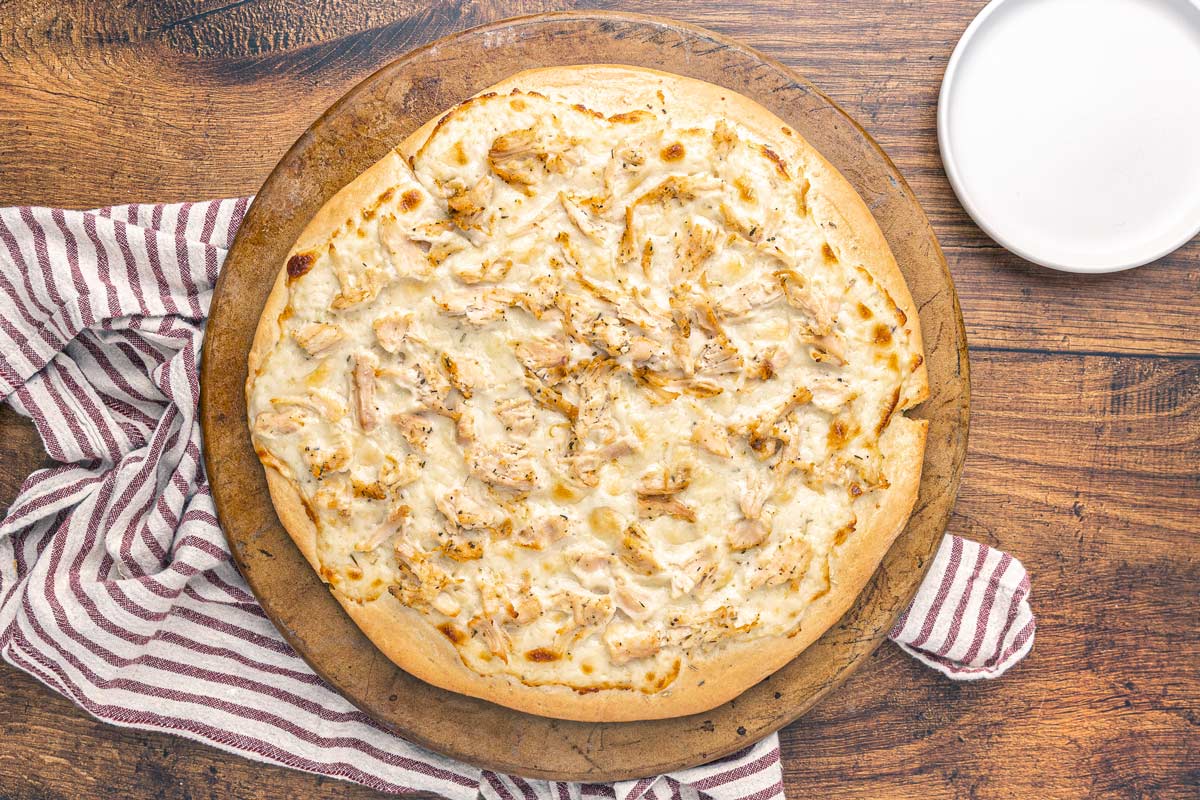 Bird's eye view of a whole baked chicken Alfredo pizza.