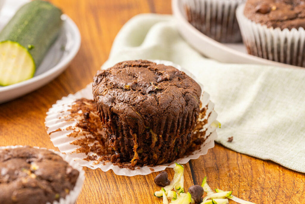 A double chocolate zucchini muffin sitting on an opened muffin liner.