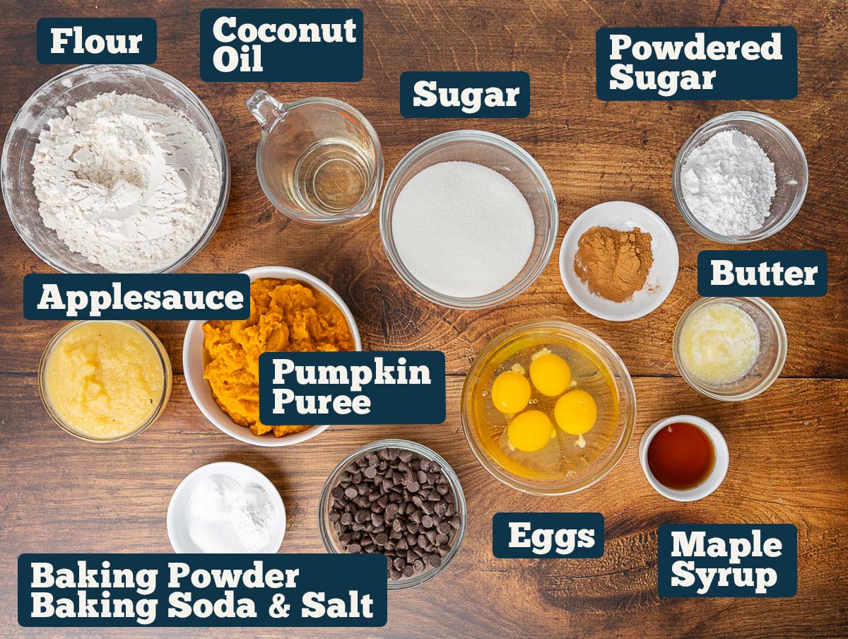 Pumpkin chocolate chip muffin ingredients: flour, coconut oil, sugar, cinnamon, baking soda, baking powder, applesauce, pumpkin pureé, eggs, powdered sugar, chocolate chips, and maple syrup.