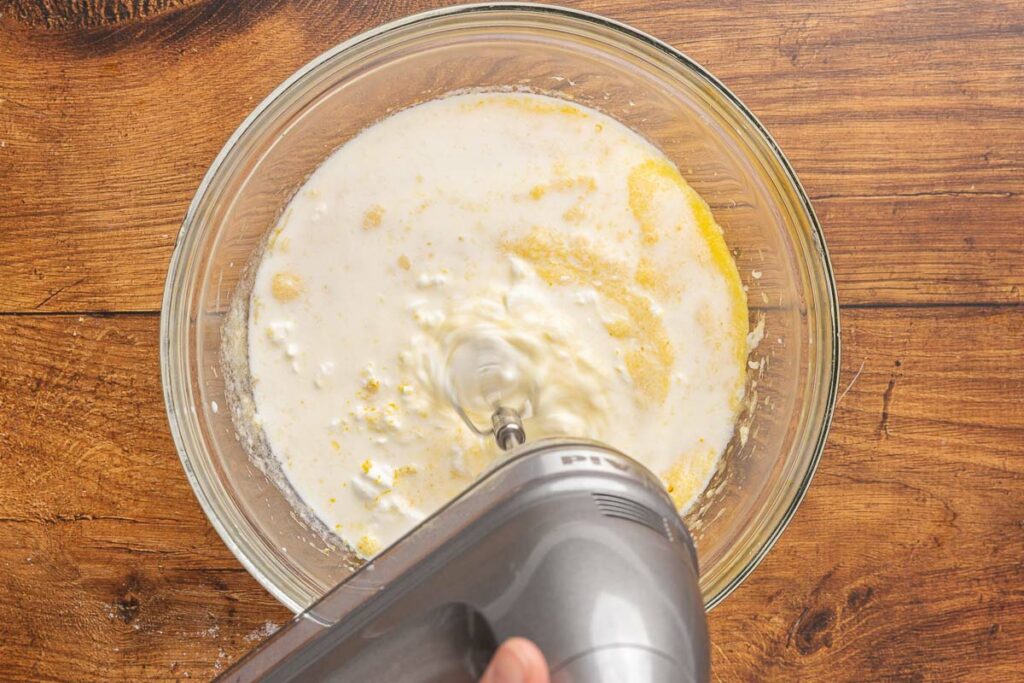 An electric mixer creaming together, cream cheese, lemon zest, and vanilla.