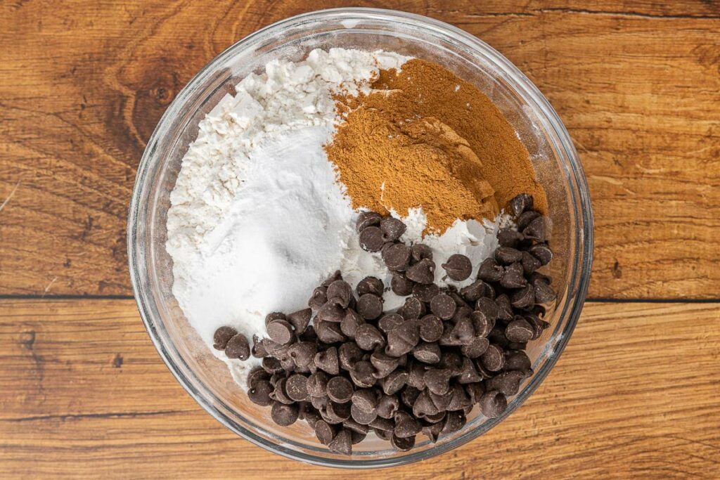 Pumpkin chocolate chip muffin dry ingredients in a bowl: flour, baking soda, baking powder, cinnamon, and chocolate chips.