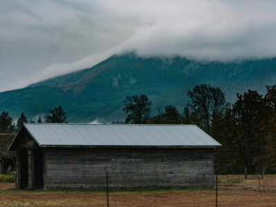 A barn with a mountain in the background.