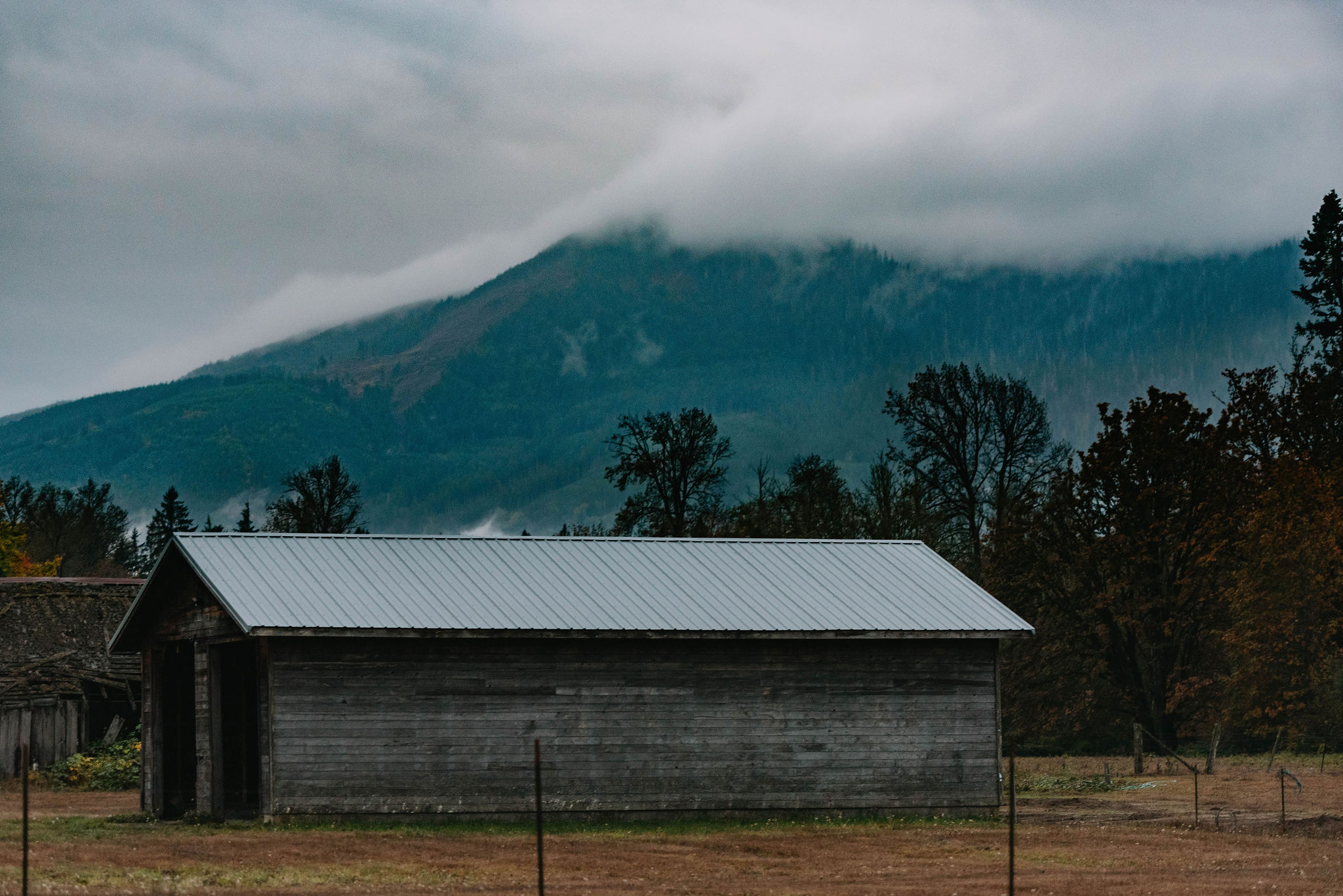 A barn with a mountain in the background.